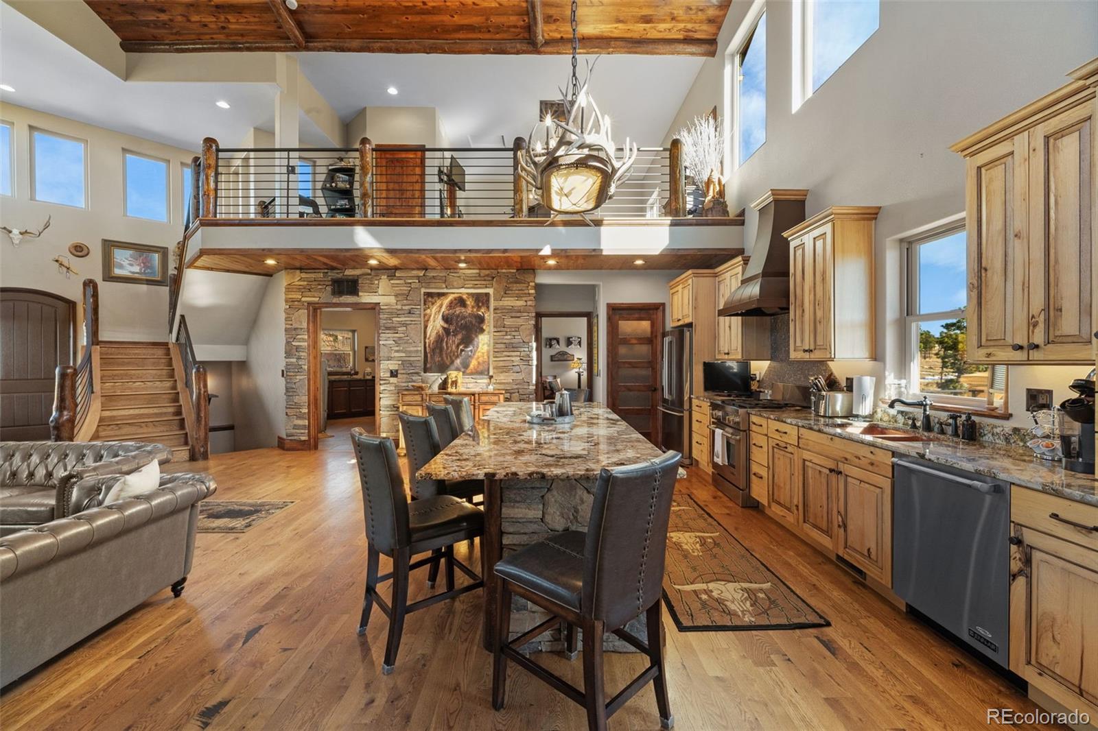 12875 Holmes Road Colorado Springs, CO 80908 - Photo 14 of 50 a kitchen with stainless steel appliances kitchen island granite countertop a table chairs in it and wooden floors