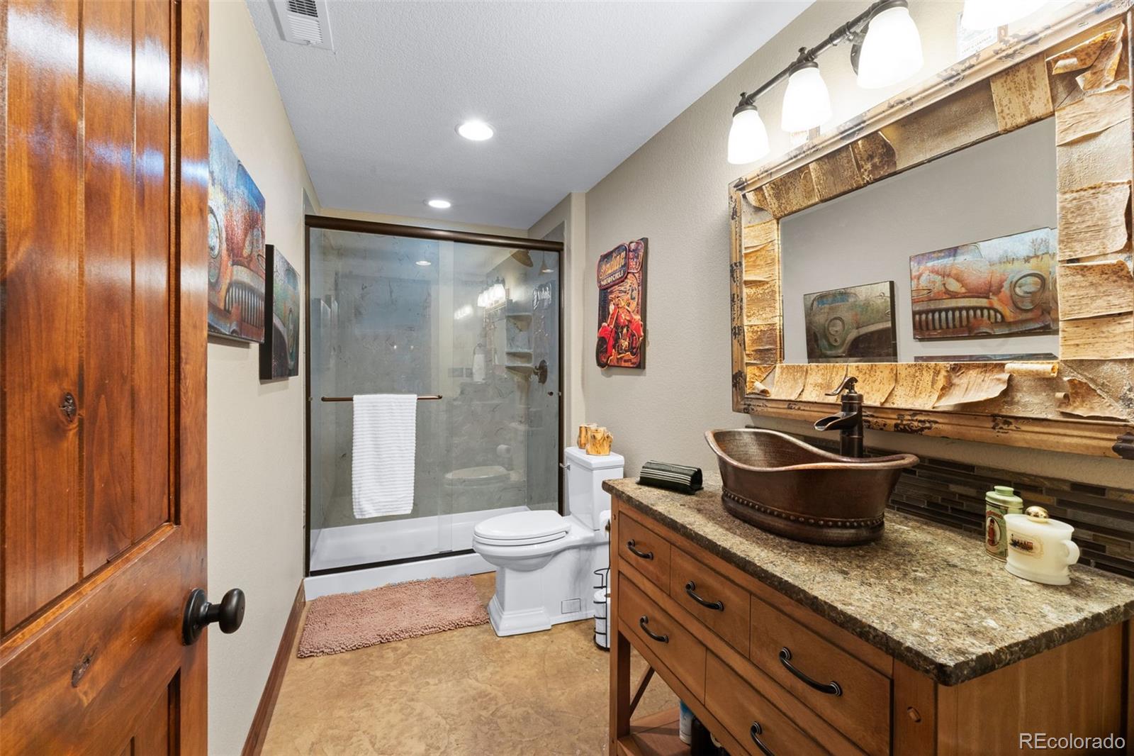 12875 Holmes Road Colorado Springs, CO 80908 - Photo 45 of 50 a bathroom with a granite countertop sink a toilet and shower