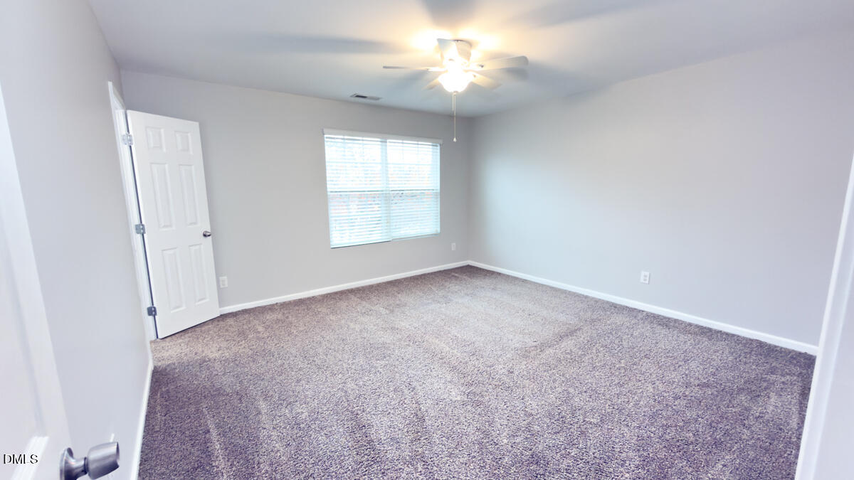 2608 Follow Me Way Raleigh, NC 27610 - Photo 17 of 32 an empty room with chandelier fan and windows