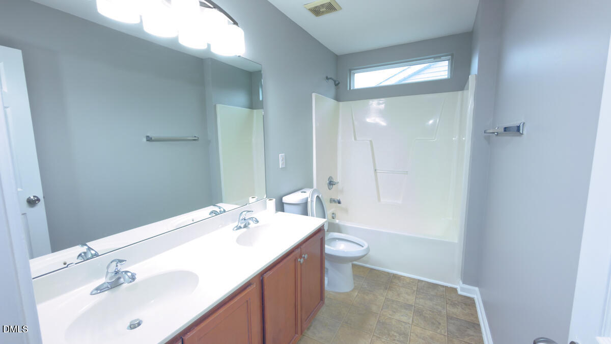 2608 Follow Me Way Raleigh, NC 27610 - Photo 18 of 32 a bathroom with a double vanity sink toilet and mirror