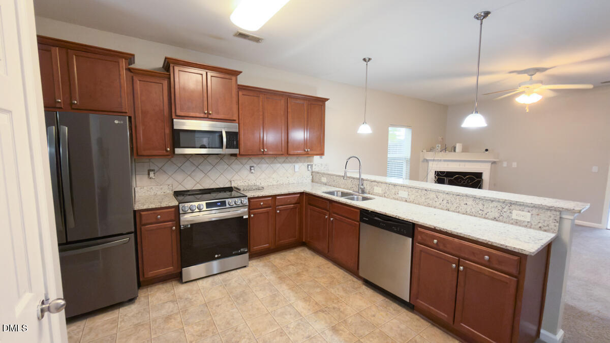 2608 Follow Me Way Raleigh, NC 27610 - Photo 6 of 32 a kitchen with stainless steel appliances granite countertop a refrigerator a sink a stove a microwave and wooden cabinets