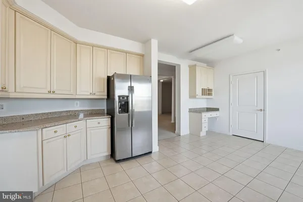a kitchen with white cabinets and refrigerator