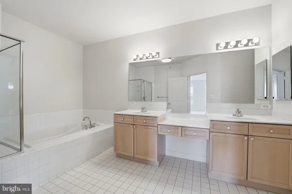 a spacious bathroom with a bathtub a double vanity sink and mirror