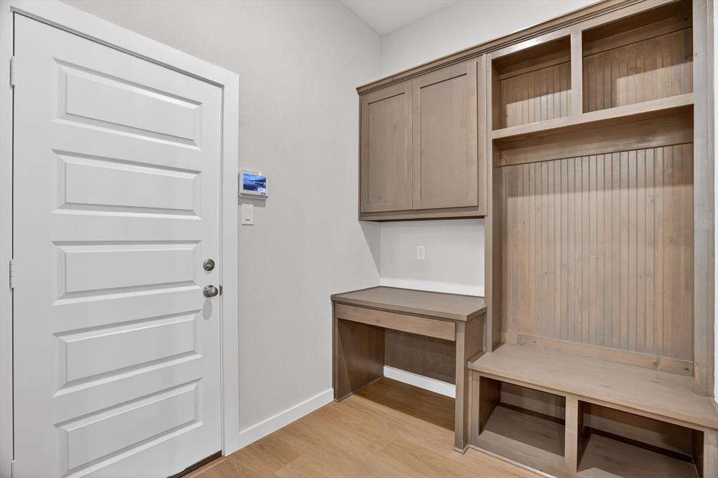321 Skeen Peak Springtown, TX 76082 - Photo 20 of 37 Mudroom featuring built-in cabinetry, an integrated desk, open shelving, a bench, and wood-finish flooring
