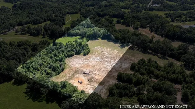 an aerial view of residential house with outdoor space and trees all around