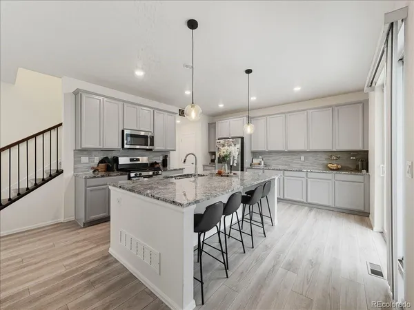 a kitchen with stainless steel appliances kitchen island granite countertop a wooden floor and white cabinets