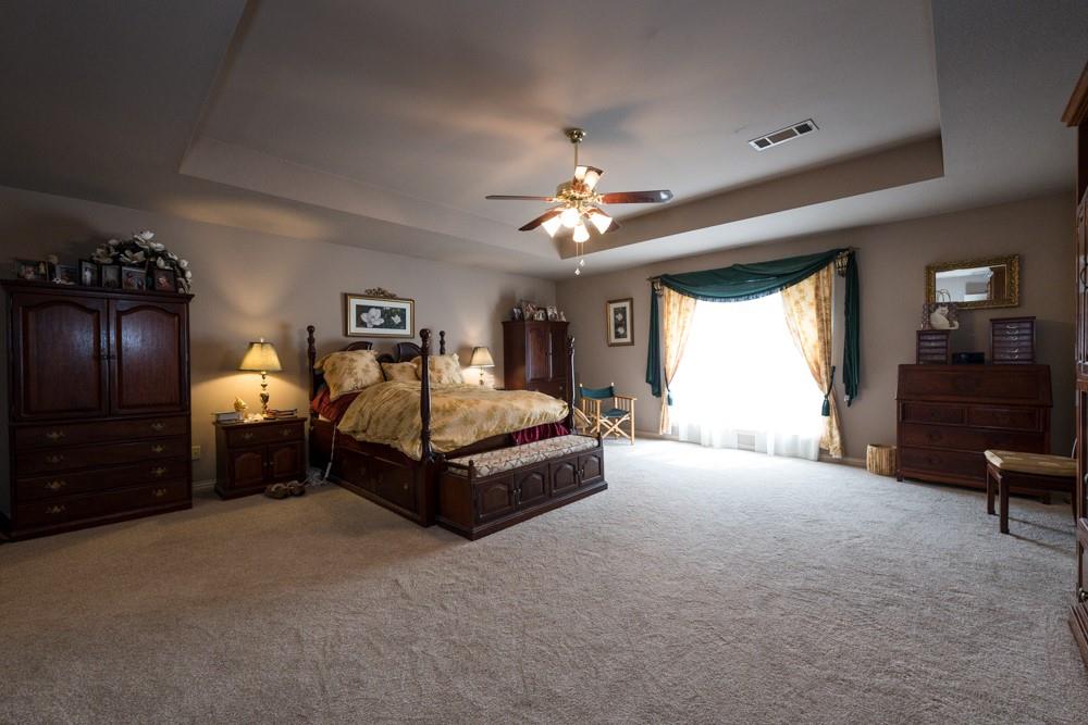 9554 David Fort Road Argyle, TX 76226 - Photo 23 of 35 a spacious bedroom with a bed and a chandelier