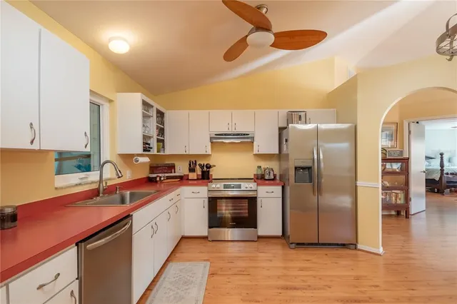 a kitchen with stainless steel appliances granite countertop a sink cabinets and wooden floor