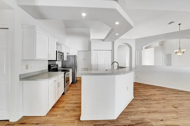 a large kitchen with stainless steel appliances lots of counter space and wooden floor