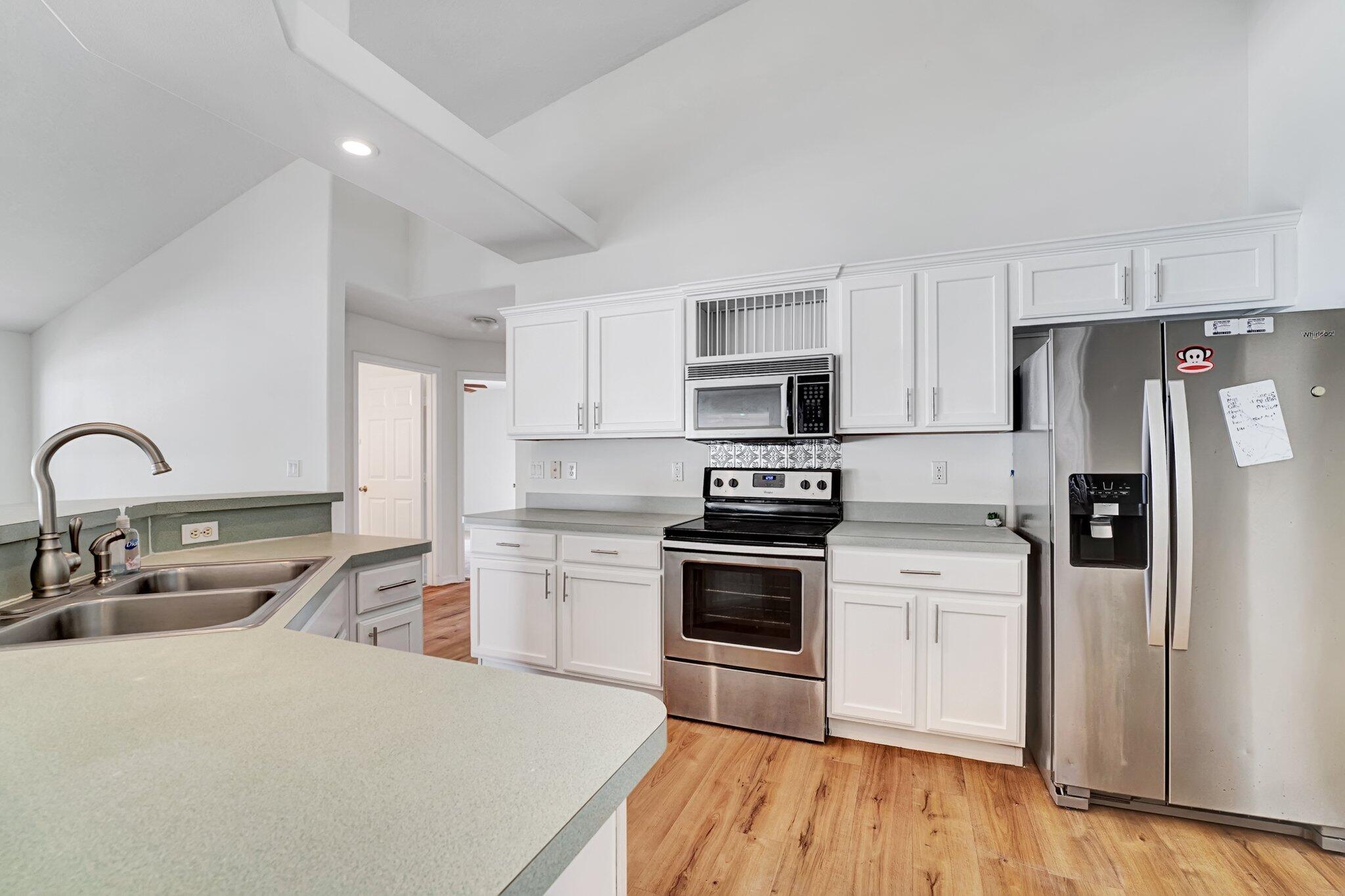 513 Southeast Cliff Road Port St. Lucie, FL 34984 - Photo 19 of 39 a kitchen with white cabinets and stainless steel appliances