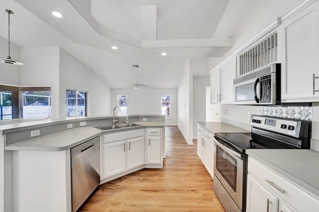 a kitchen with stainless steel appliances granite countertop a sink stove and cabinets