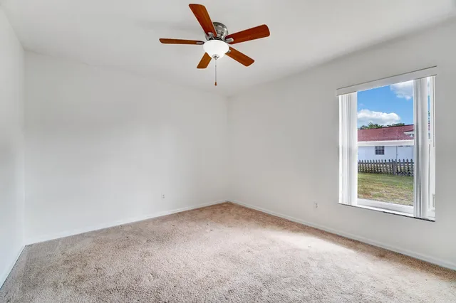an empty room with a window and a ceiling fan