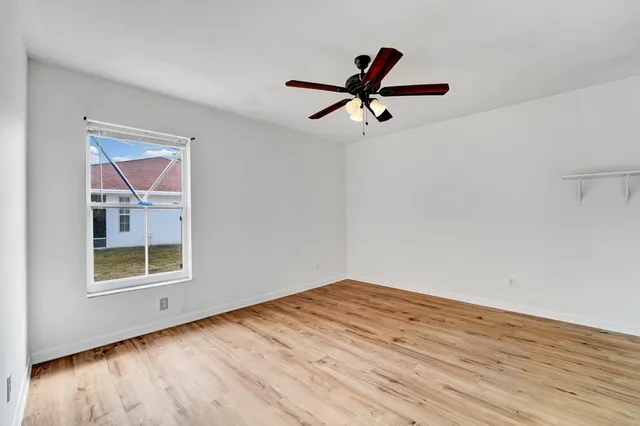 a view of empty room with wooden floor and window