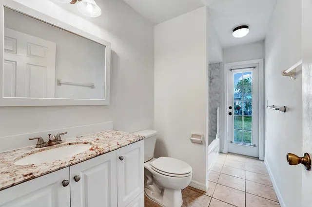 a bathroom with a granite countertop sink a toilet and shower