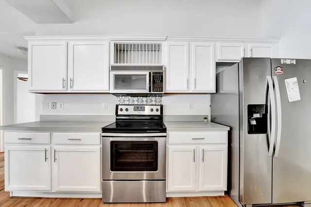 a kitchen with white cabinets and stainless steel appliances