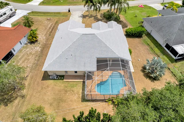 an aerial view of a house with swimming pool and large trees