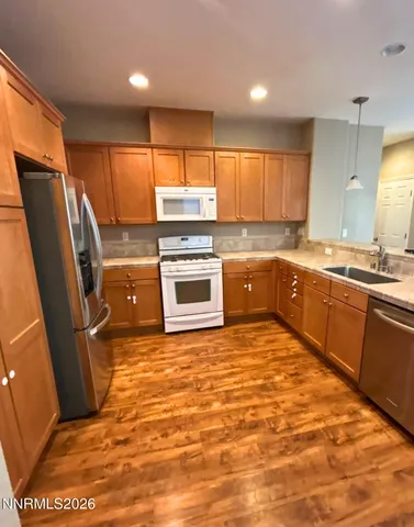 a kitchen with stainless steel appliances granite countertop a sink stove refrigerator and cabinets