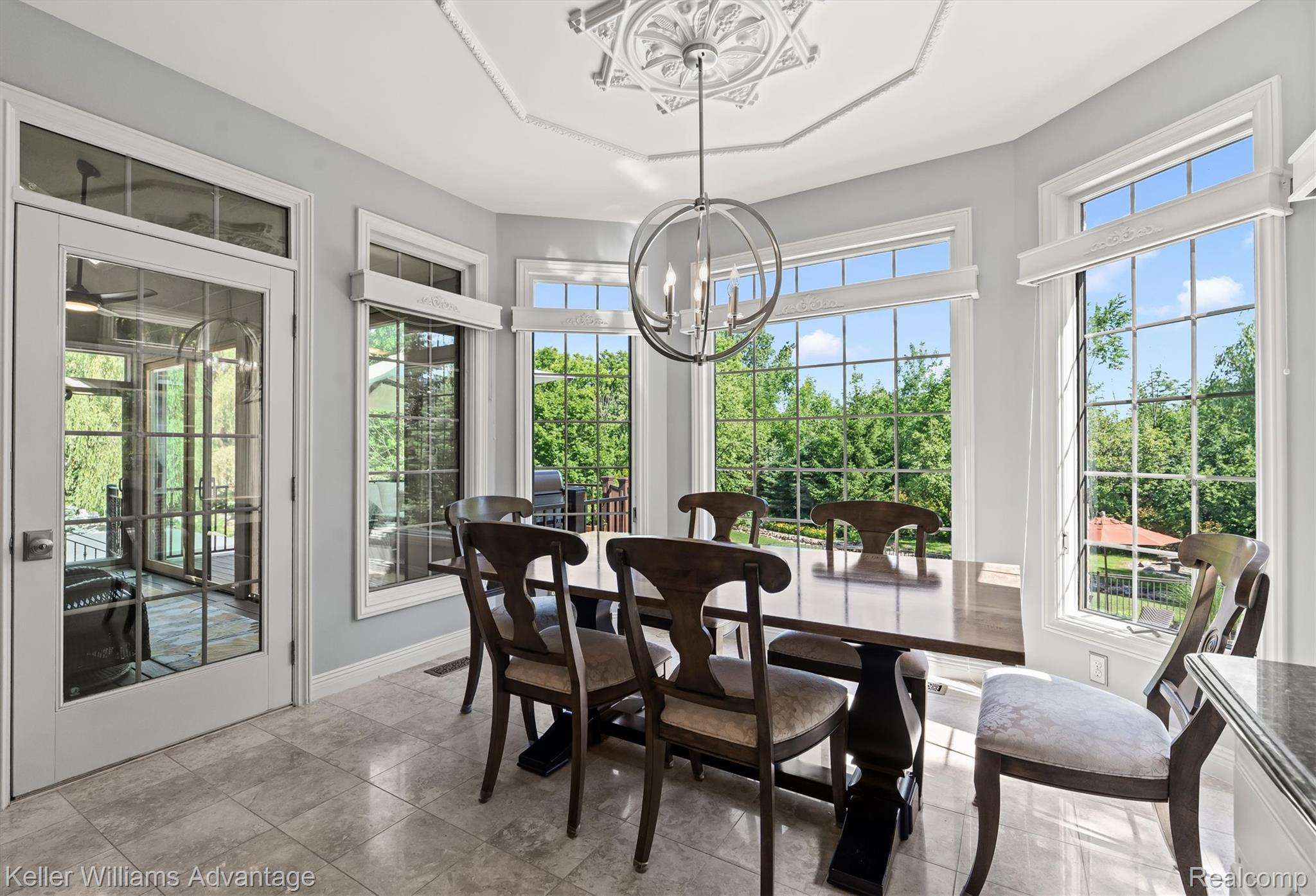 22878 Tree Top Court South Lyon, MI 48178 - Photo 11 of 75 Dining area with expansive window wall, tray ceiling with decorative medallion, and a contemporary chandelier