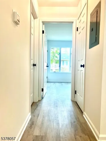 a view of a hallway with wooden floor and a bathroom