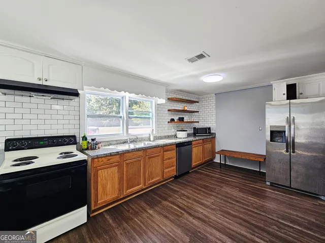 a kitchen with stainless steel appliances kitchen island granite countertop a stove a sink and a refrigerator