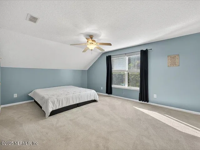 a bedroom with a large bed chandelier and a window
