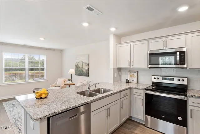 a kitchen with stainless steel appliances granite countertop a sink a stove a microwave a counter space and cabinets