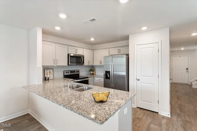 a kitchen with stainless steel appliances granite countertop a sink refrigerator and microwave