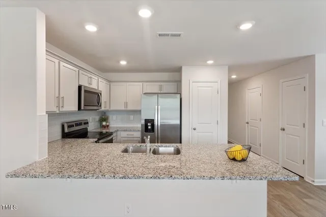 a kitchen with stainless steel appliances granite countertop sink stove refrigerator and cabinets