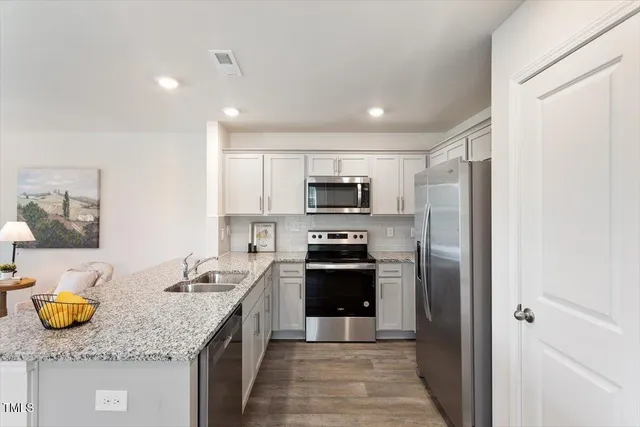 a kitchen with stainless steel appliances granite countertop a sink stove and refrigerator