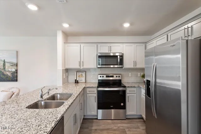 a kitchen with stainless steel appliances granite countertop a refrigerator a sink a stove a microwave and island