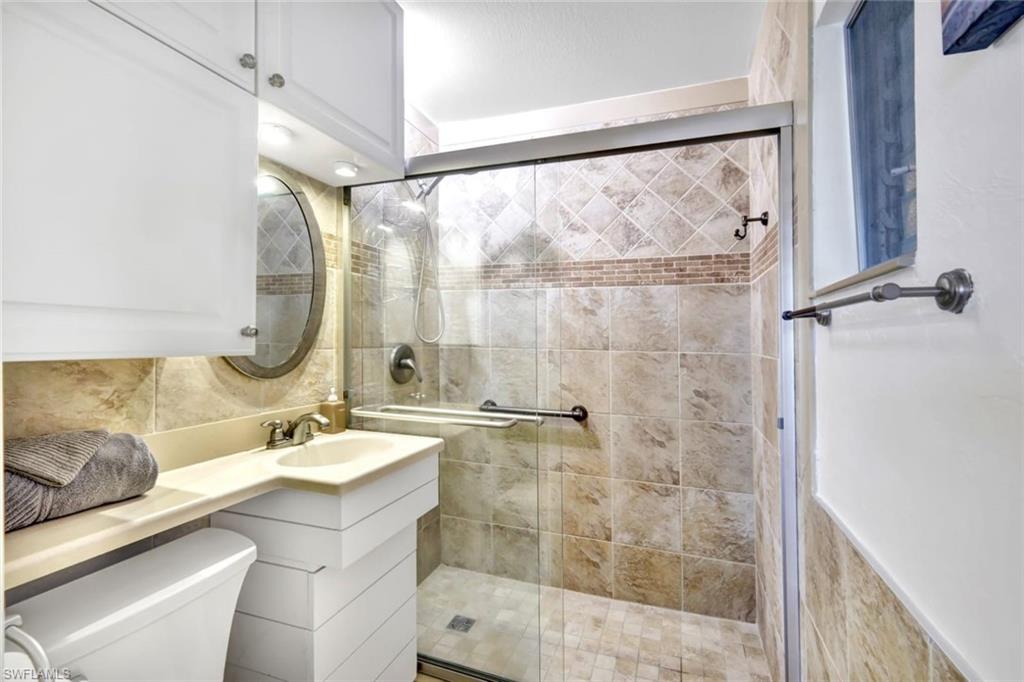 2047 Harbor Lane Naples, FL 34104 - Photo 16 of 27 Bathroom featuring a shower stall, vanity, and tasteful backsplash