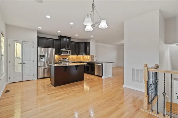 a large kitchen with stainless steel appliances kitchen island granite countertop a stove a refrigerator a sink a microwave and island with wooden floor