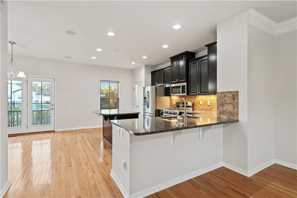 a kitchen with stainless steel appliances granite countertop a sink and wooden floor