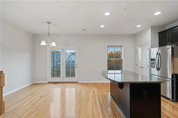 a view of a kitchen with refrigerator and wooden floor