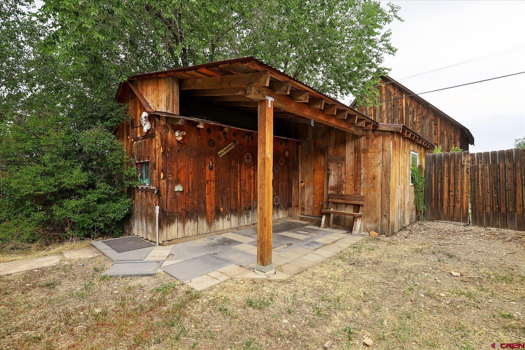 438 Bauer Avenue Mancos, CO 81328 - Photo 17 of 30 a view of a wooden house with large trees and wooden fence