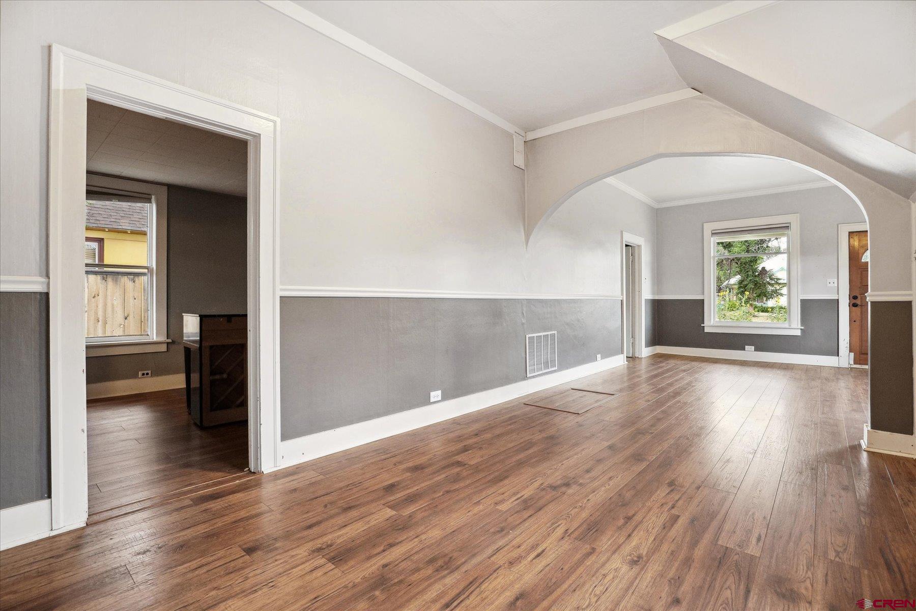 438 Bauer Avenue Mancos, CO 81328 - Photo 7 of 30 an empty room with wooden floor and a kitchen
