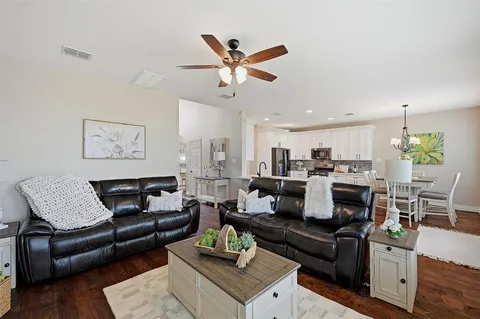 a living room with furniture kitchen view and a chandelier