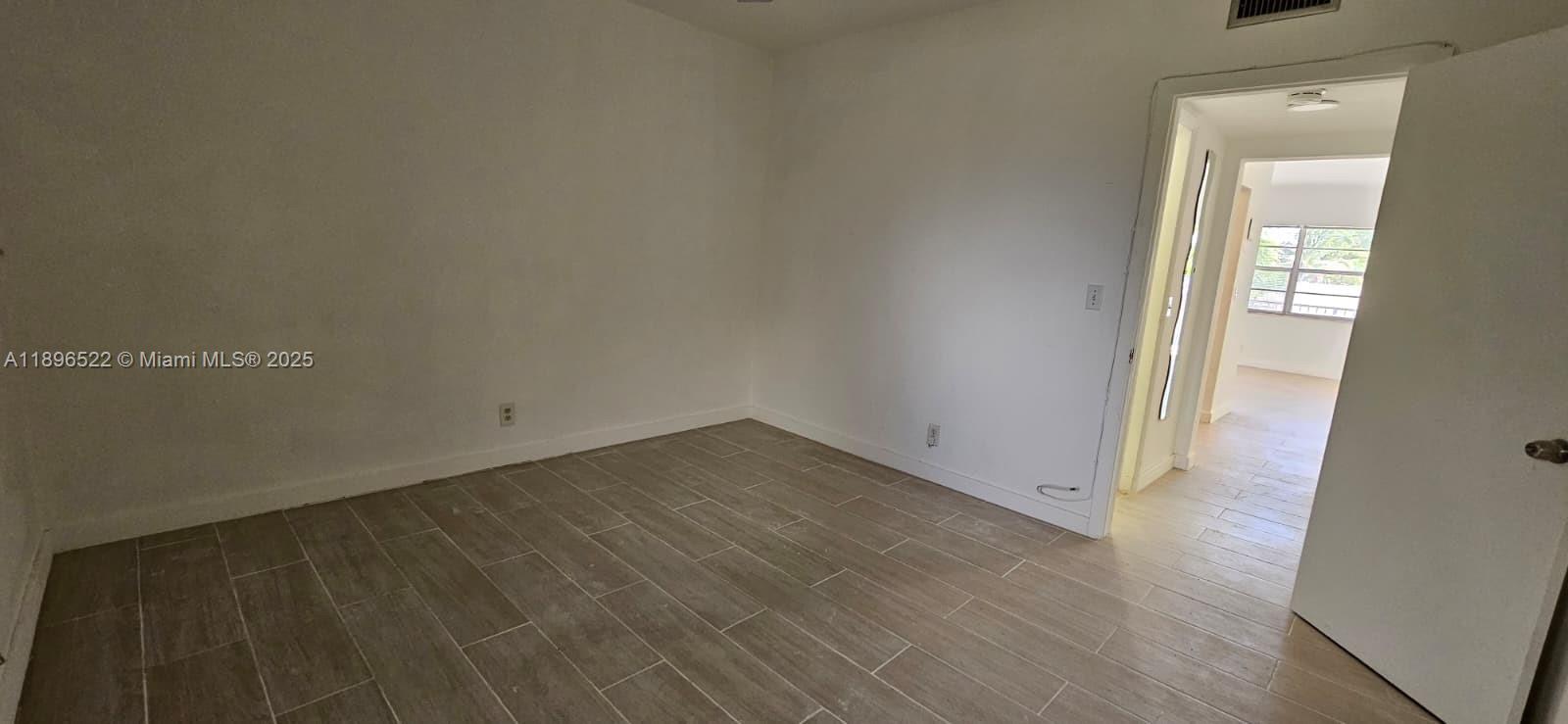 230 Southwest 11th Avenue, Unit 14 Hallandale Beach, FL 33009 - Photo 13 of 20 an empty room with wooden floor and windows