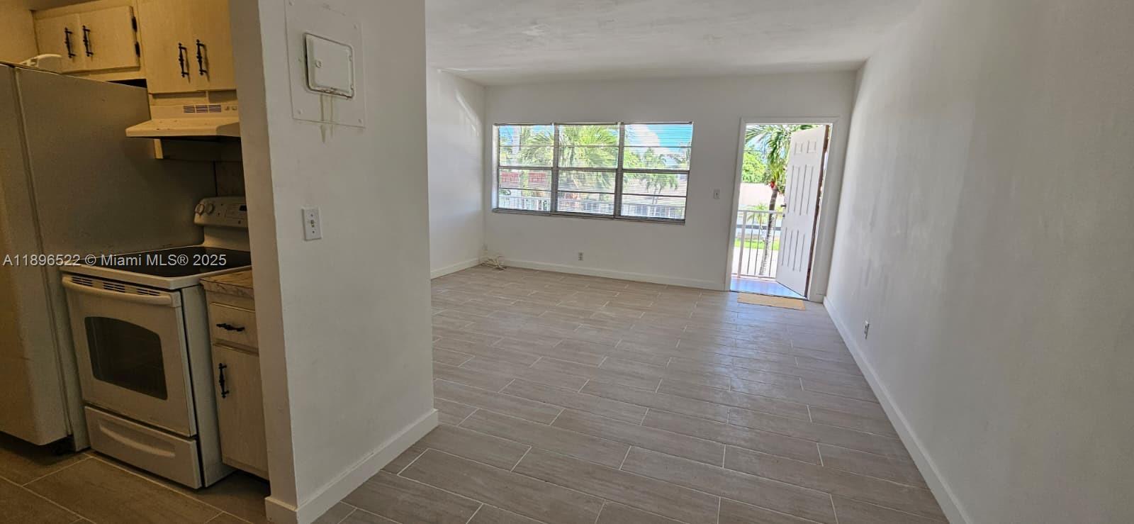 230 Southwest 11th Avenue, Unit 14 Hallandale Beach, FL 33009 - Photo 4 of 20 a view of a kitchen in an empty room with a window and fire place