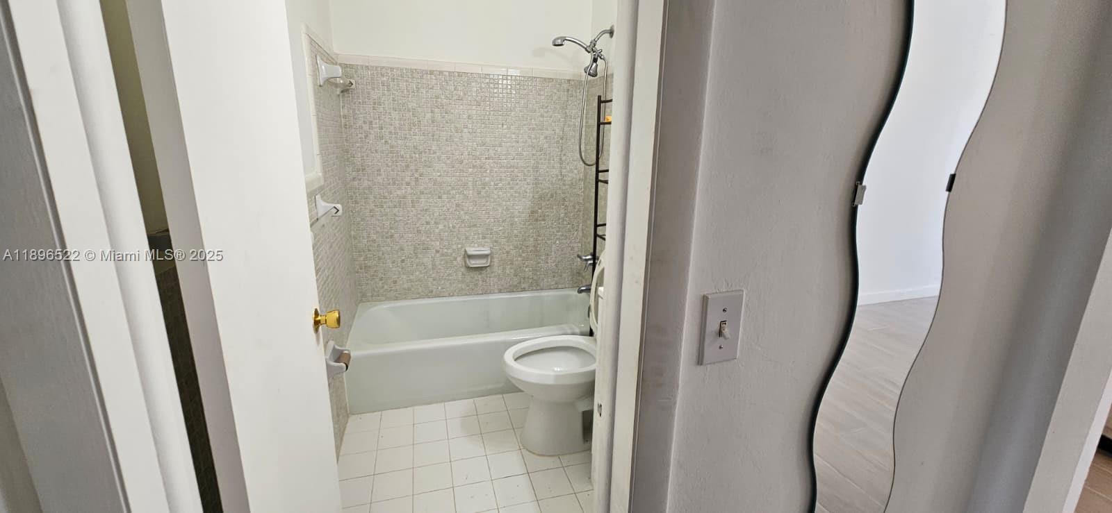 230 Southwest 11th Avenue, Unit 14 Hallandale Beach, FL 33009 - Photo 9 of 20 a bathroom with a tub and a glass door