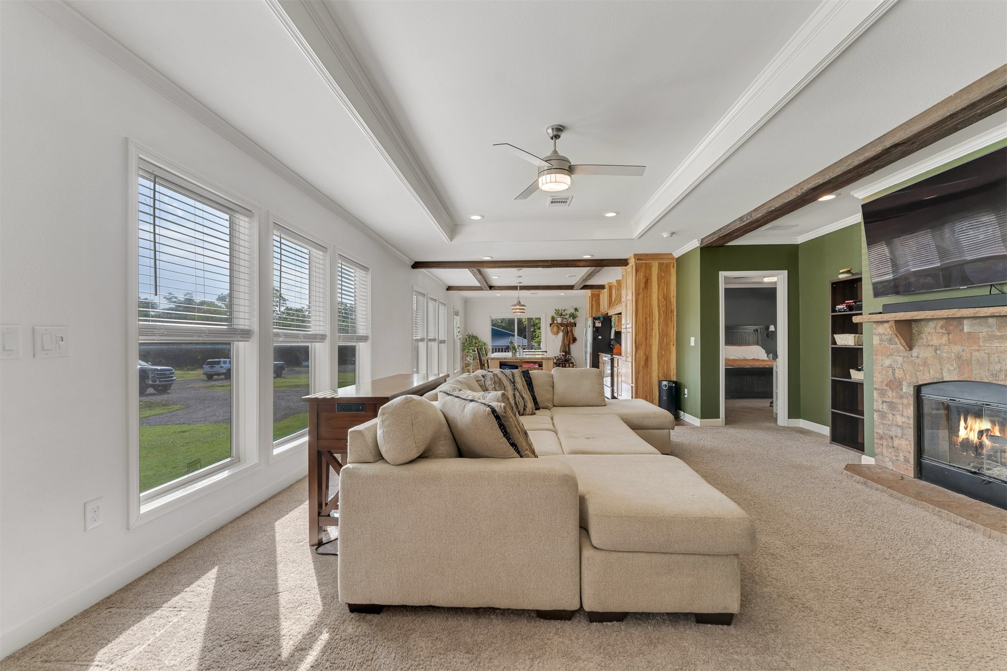 15291 East 400 Road Claremore, OK 74017 - Photo 28 of 96 Tray ceiling with a ceiling fan, stone-clad fireplace, wood beams, and multiple windows