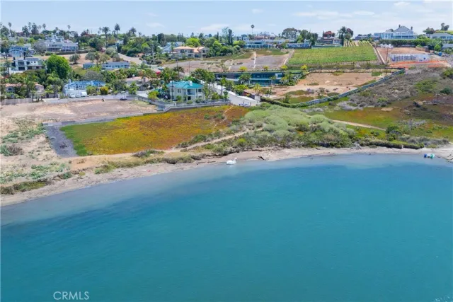 an aerial view of ocean and residential houses with outdoor space