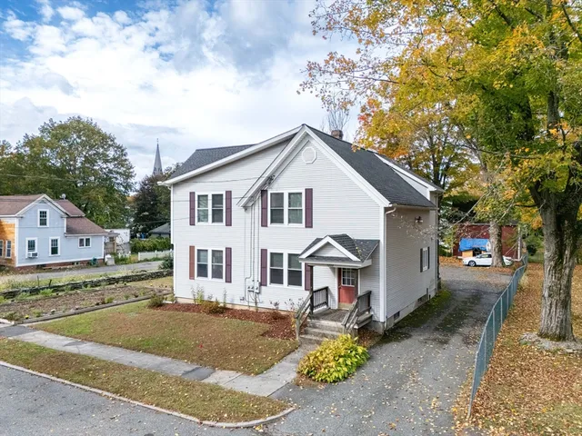 a view of a white house next to a road and yard
