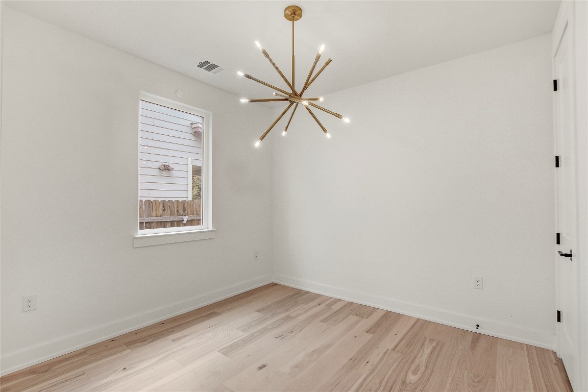4127 East 12th Street, Unit 2 Austin, TX 78721 - Photo 12 of 28 Unfurnished room featuring a chandelier, light wood-style flooring, and baseboards