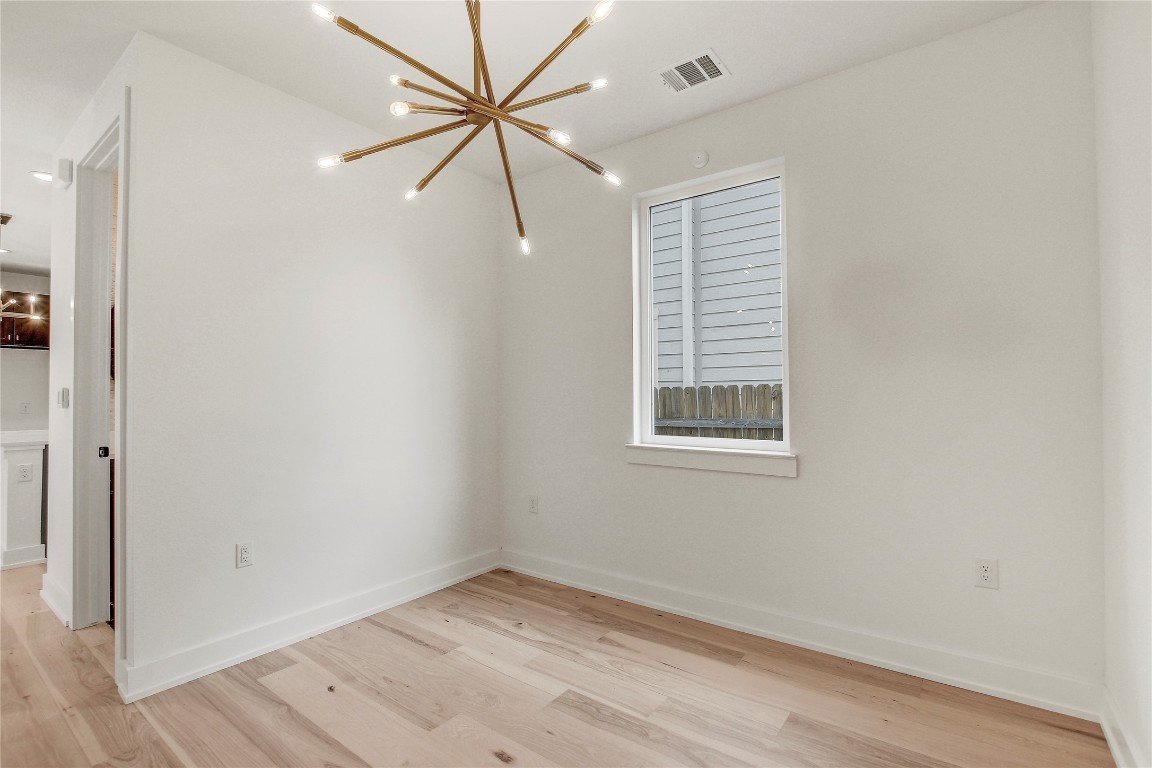4127 East 12th Street, Unit 2 Austin, TX 78721 - Photo 13 of 28 Empty room featuring a chandelier, light wood-style flooring, and baseboards