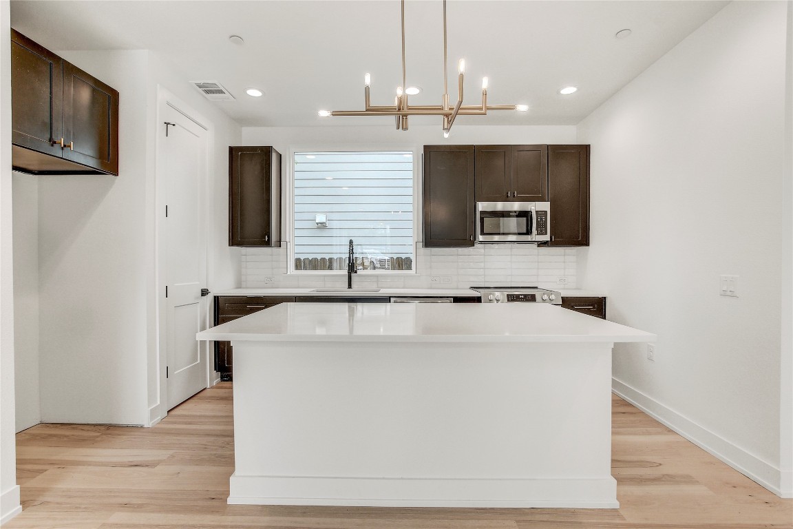 4127 East 12th Street, Unit 2 Austin, TX 78721 - Photo 15 of 28 Kitchen with appliances with stainless steel finishes, a sink, backsplash, dark brown cabinets, and recessed lighting