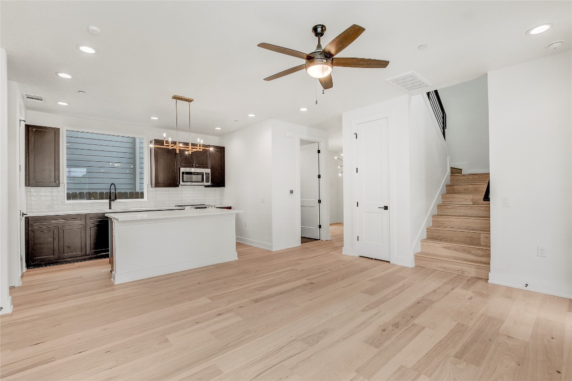 4127 East 12th Street, Unit 2 Austin, TX 78721 - Photo 19 of 28 Kitchen with stainless steel microwave, dark brown cabinets, backsplash, light wood-type flooring, and recessed lighting