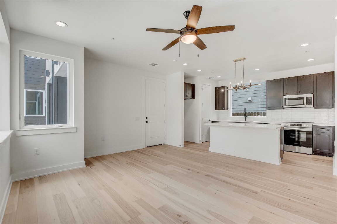4127 East 12th Street, Unit 2 Austin, TX 78721 - Photo 2 of 28 Kitchen with appliances with stainless steel finishes, light countertops, light wood-style floors, dark brown cabinets, and ceiling fan