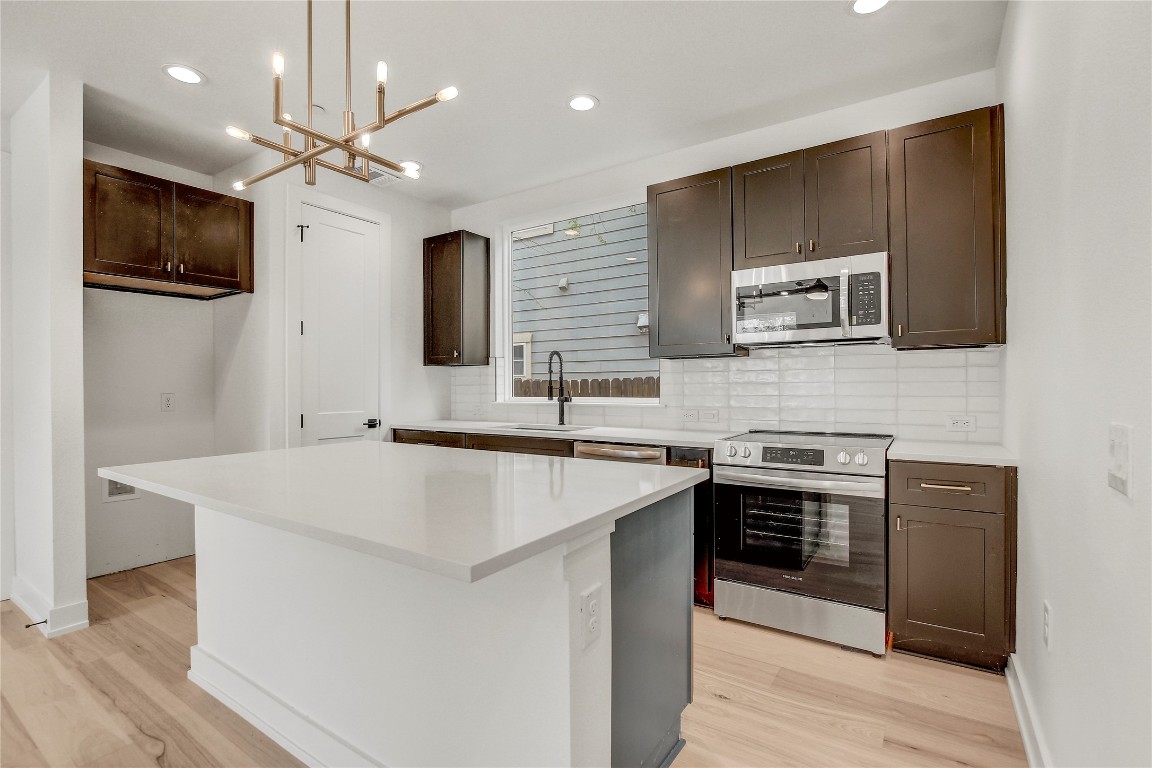 4127 East 12th Street, Unit 2 Austin, TX 78721 - Photo 4 of 28 Kitchen with appliances with stainless steel finishes, light wood-style floors, tasteful backsplash, dark brown cabinets, and recessed lighting