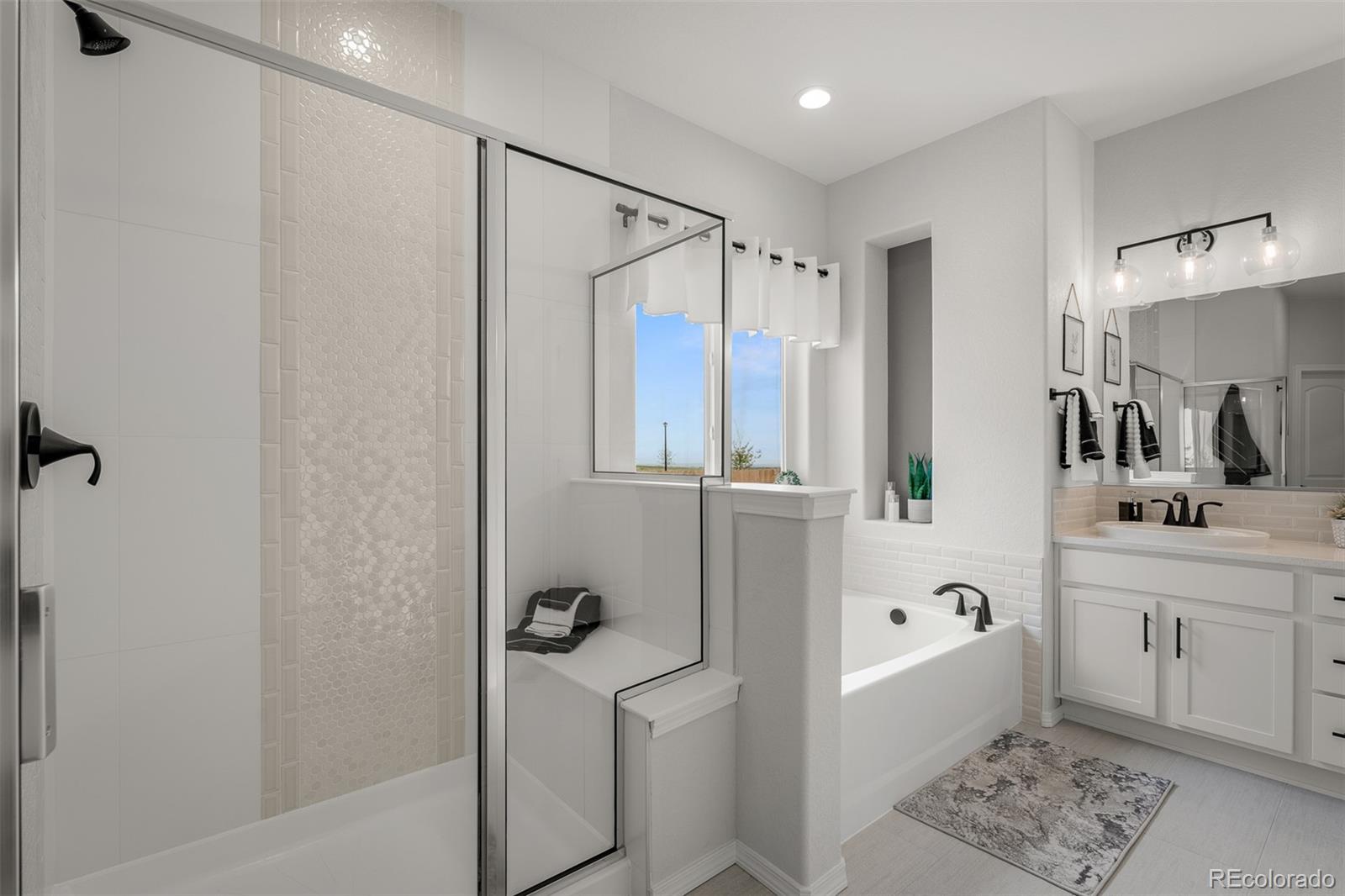 13410 New Ranch Drive Peyton, CO 80831 - Photo 25 of 50 a bathroom with a double vanity sink a mirror a bathtub and shower